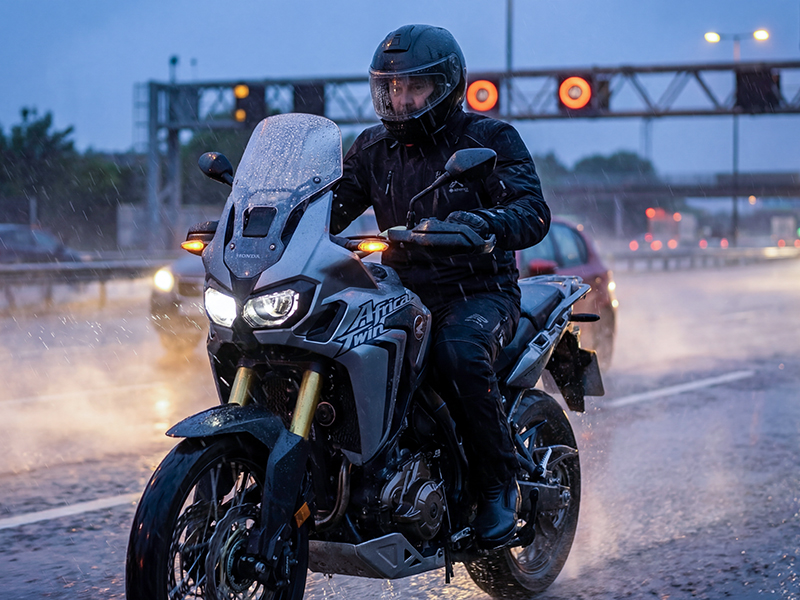 Man riding Honda Africa Twin wearing Rukka Nivala 3 suit in rain on UK motorway